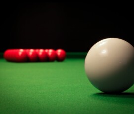 A detailed view of billiard balls on a snooker table with a focus on the white ball.
