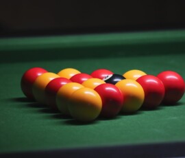 Close-up view of vibrant billiard balls arranged on a green pool table, ready for a game.
