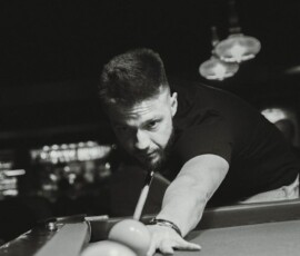 Black and white image of a man concentrating during a billiards game, illustrating intense focus.